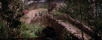 Movie still from “Brigadoon” (1954), directed by Vincente Minnelli – Two men are standing near a stone bridge; Extreme Wide shot, High angle