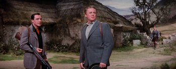 Movie still from “Brigadoon” (1954), directed by Vincente Minnelli – A man wearing a suit and holding a hat in his hand; Medium shot, Low angle