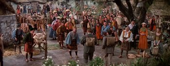 Movie still from “Brigadoon” (1954), directed by Vincente Minnelli – A group of men in traditional clothing are standing in a crowd; Wide shot, High angle