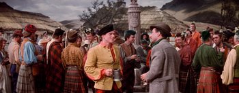 Movie still from “Brigadoon” (1954), directed by Vincente Minnelli – A group of men standing next to each other on a street; Medium shot, Over the shoulder angle