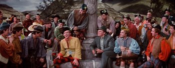 Movie still from “Brigadoon” (1954), directed by Vincente Minnelli – A group of men sitting on top of a stone pillar; Wide shot, High angle