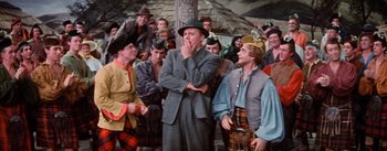 Movie still from “Brigadoon” (1954), directed by Vincente Minnelli – A group of men in a crowd of people; Medium shot, Over the shoulder angle