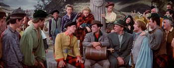 Movie still from “Brigadoon” (1954), directed by Vincente Minnelli – A group of men and women sitting on the ground; Wide shot, High angle