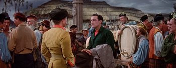 Movie still from “Brigadoon” (1954), directed by Vincente Minnelli – A group of people standing next to each other on a street; Medium shot, Over the shoulder angle