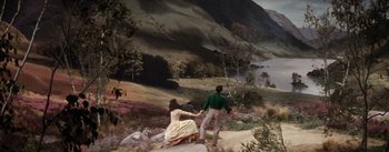 Movie still from “Brigadoon” (1954), directed by Vincente Minnelli – A man and a woman holding hands while standing on a hill; Extreme Wide shot, High angle