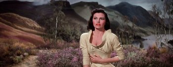 Movie still from “Brigadoon” (1954), directed by Vincente Minnelli – A woman in a white dress standing in front of a field; Medium shot, Low angle