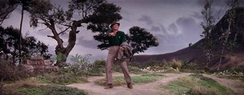 Movie still from “Brigadoon” (1954), directed by Vincente Minnelli – A man standing on a dirt road pointing to the sky; Wide shot, Low angle