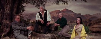 Movie still from “Brigadoon” (1954), directed by Vincente Minnelli – Two men sitting next to each other on top of a rock; Medium shot, Low angle
