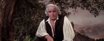 Movie still from “Brigadoon” (1954), directed by Vincente Minnelli – An older man with a white beard sitting on a bench; Close Up shot, Low angle