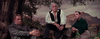 Movie still from “Brigadoon” (1954), directed by Vincente Minnelli – An older man sitting on a rock in front of a tree; Medium shot, Low angle