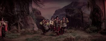 Movie still from “Brigadoon” (1954), directed by Vincente Minnelli – A group of men standing next to each other in a field; Wide shot, Low angle