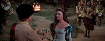 Movie still from “Brigadoon” (1954), directed by Vincente Minnelli – A woman in a white dress standing in front of a person; Medium shot, Over the shoulder angle