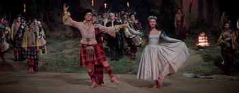 Movie still from “Brigadoon” (1954), directed by Vincente Minnelli – A group of people in costumes dancing in a field; Wide shot, Low angle