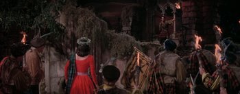 Movie still from “Brigadoon” (1954), directed by Vincente Minnelli – A group of people standing in a room with trees; Wide shot, Low angle