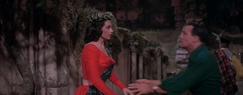 Movie still from “Brigadoon” (1954), directed by Vincente Minnelli – A woman in a red dress is shaking someone's hand; Medium shot, Over the shoulder angle