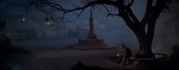 Movie still from “Brigadoon” (1954), directed by Vincente Minnelli – A man sitting on the ground in front of a statue; Wide shot, High angle