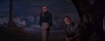Movie still from “Brigadoon” (1954), directed by Vincente Minnelli – Two men standing next to each other on a field; Medium shot, Low angle