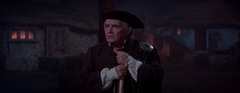 Movie still from “Brigadoon” (1954), directed by Vincente Minnelli – A man in a hat and a long coat holding a cane; Medium shot, Low angle