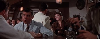 Movie still from “Brigadoon” (1954), directed by Vincente Minnelli – A group of people sitting at a table in a restaurant; Medium shot, Over the shoulder angle