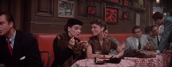 Movie still from “Brigadoon” (1954), directed by Vincente Minnelli – A couple of women sitting at a table eating food; Medium shot, Low angle
