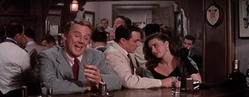 Movie still from “Brigadoon” (1954), directed by Vincente Minnelli – A group of people sitting at a table; Medium shot, Over the shoulder angle