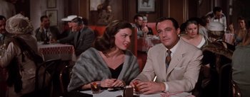 Movie still from “Brigadoon” (1954), directed by Vincente Minnelli – A man and a woman sitting at a table in a restaurant; Medium shot, Over the shoulder angle