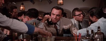 Movie still from “Brigadoon” (1954), directed by Vincente Minnelli – A man sitting at a table talking on a phone; Close Up shot, Low angle