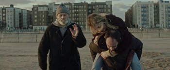 A man and a woman being pulled by a man in a coat