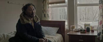 A man sitting on a bed in front of a window