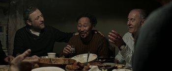 A man sitting at a dinner table holding a drink