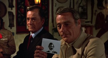 Movie still from “Bring Me the Head of Alfredo Garcia” (1974), directed by Sam Peckinpah – Two men holding up a picture of a young man; Close Up shot, Over the shoulder angle