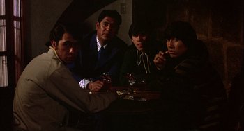 Movie still from “Bring Me the Head of Alfredo Garcia” (1974), directed by Sam Peckinpah – A group of people sitting around a table with drinks; Medium shot, High angle