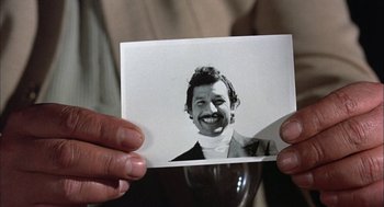 Movie still from “Bring Me the Head of Alfredo Garcia” (1974), directed by Sam Peckinpah – A man holding a picture of a smiling man; Extreme Close Up shot, Low angle