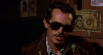 Movie still from “Bring Me the Head of Alfredo Garcia” (1974), directed by Sam Peckinpah – A person wearing sunglasses; Close Up shot, Low angle