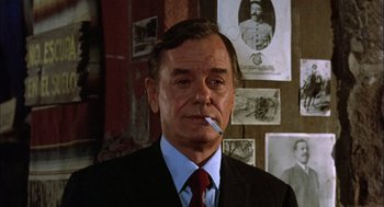 Movie still from “Bring Me the Head of Alfredo Garcia” (1974), directed by Sam Peckinpah – An older man wearing a suit and tie smoking a cigarette; Close Up shot, Low angle