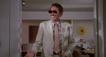 Movie still from “Bring Me the Head of Alfredo Garcia” (1974), directed by Sam Peckinpah – A man in a suit and tie standing in front of a table; Medium shot, Low angle