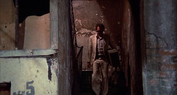 Movie still from “Bring Me the Head of Alfredo Garcia” (1974), directed by Sam Peckinpah – A man in a suit and tie walking down a staircase; Wide shot, Low angle