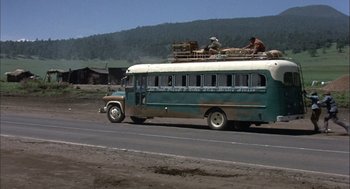 Movie still from “Bring Me the Head of Alfredo Garcia” (1974), directed by Sam Peckinpah – An old school bus is parked on the side of the road; Wide shot, Low angle