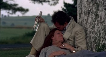 Movie still from “Bring Me the Head of Alfredo Garcia” (1974), directed by Sam Peckinpah – A man and a woman sitting next to a tree; Medium shot, High angle