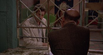 Movie still from “Bring Me the Head of Alfredo Garcia” (1974), directed by Sam Peckinpah – Two men and a woman are sitting at a table in front of a mirror; Medium shot, Over the shoulder angle