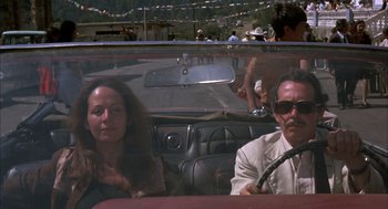 Movie still from “Bring Me the Head of Alfredo Garcia” (1974), directed by Sam Peckinpah – A man and a woman sitting in the back seat of a car; Medium shot, High angle