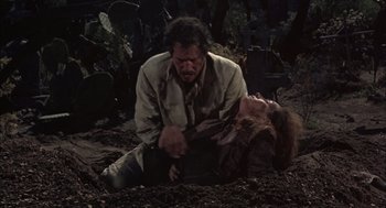 Movie still from “Bring Me the Head of Alfredo Garcia” (1974), directed by Sam Peckinpah – A man and a woman in the dirt with cacti in the background; Medium shot, High angle