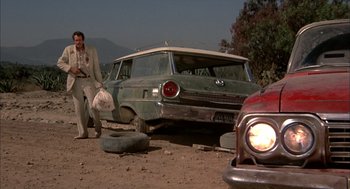 Movie still from “Bring Me the Head of Alfredo Garcia” (1974), directed by Sam Peckinpah – An old car sitting on the side of a road; Wide shot, Low angle