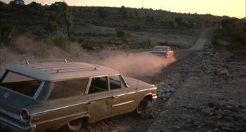 Movie still from “Bring Me the Head of Alfredo Garcia” (1974), directed by Sam Peckinpah – Two cars are driving down a dirt road; Wide shot, Low angle