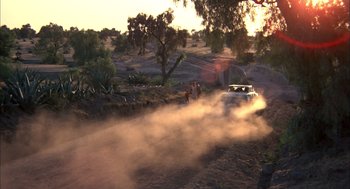 Movie still from “Bring Me the Head of Alfredo Garcia” (1974), directed by Sam Peckinpah – A car driving on a dirt road near some trees; Extreme Wide shot, Low angle