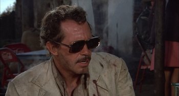 Movie still from “Bring Me the Head of Alfredo Garcia” (1974), directed by Sam Peckinpah – A person wearing a suit and sunglasses; Close Up shot, Over the shoulder angle