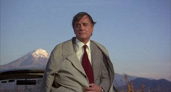 Movie still from “Bring Me the Head of Alfredo Garcia” (1974), directed by Sam Peckinpah – A man in a suit and tie standing in front of a mountain; Medium shot, Low angle