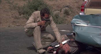 Movie still from “Bring Me the Head of Alfredo Garcia” (1974), directed by Sam Peckinpah – A man is on the side of the road while another man is on the side of the road; Medium shot, High angle