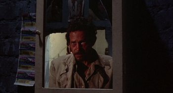 Movie still from “Bring Me the Head of Alfredo Garcia” (1974), directed by Sam Peckinpah – A man is looking into a mirror in a room; Close Up shot, Over the shoulder angle