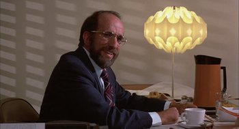 Movie still from “Bring Me the Head of Alfredo Garcia” (1974), directed by Sam Peckinpah – A man sitting at a table in front of a lamp; Close Up shot, Low angle
